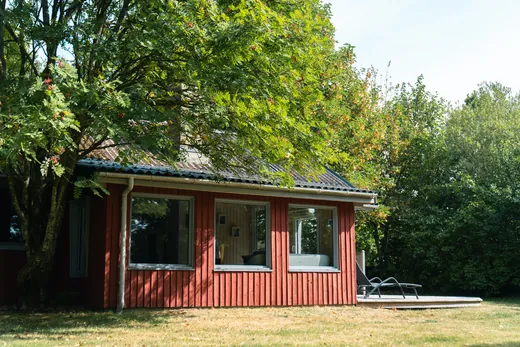 Das Ferienhaus von der Seite, mit Terrasse und Liegestühlen.