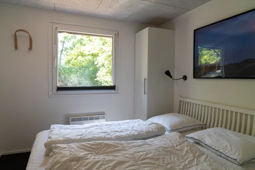 Schlafzimmer mit Doppelbett und Fenster zu den Bäumen.