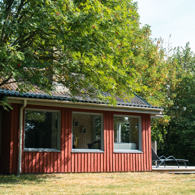 Das Ferienhaus von der Seite mit Terrasse und Liegestuhl
