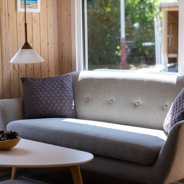 Der Wintergarten mit Sofa und großen Fenstern zum Garten